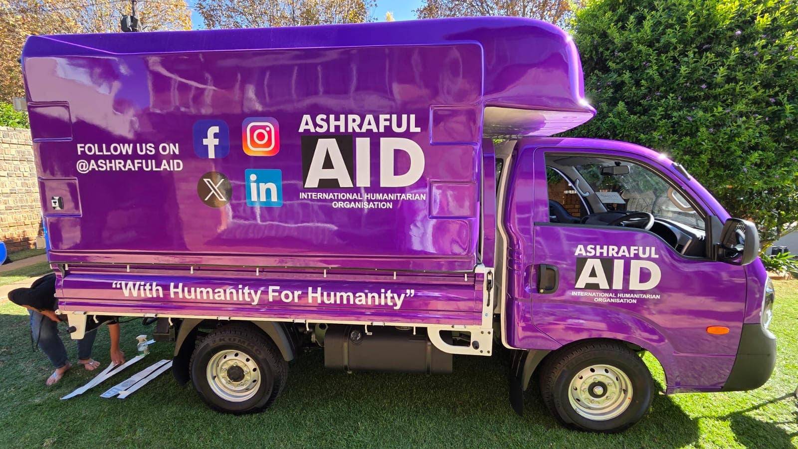 Delivery truck in a full purple Ashraful Aid wrap, photographed side-on after installation