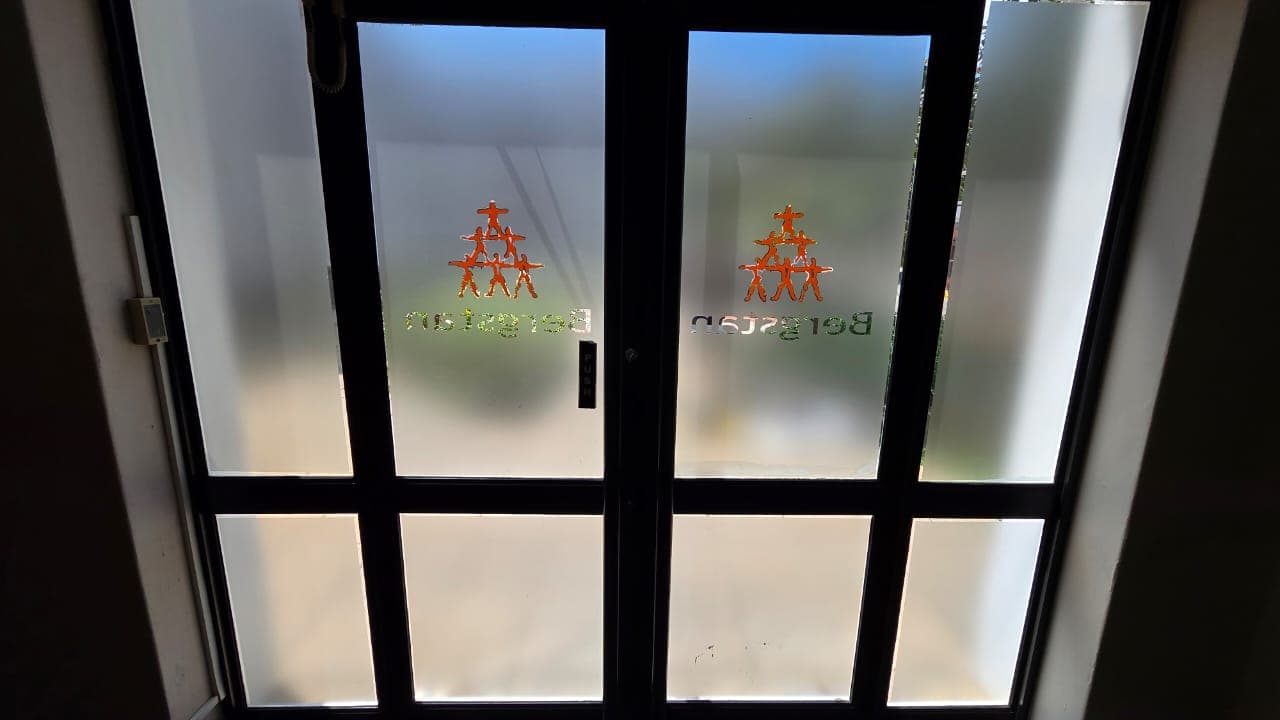 Frosted vinyl privacy film with orange logo cutouts on glass office doors