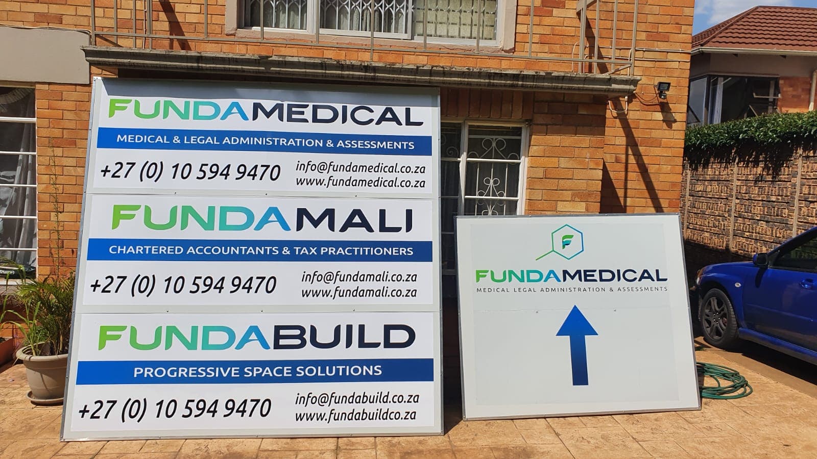 Printed directional and company boards for the Funda group mounted outside a brick building