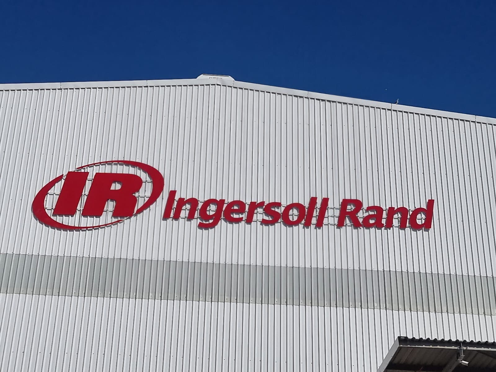 Red Ingersoll Rand channel letters mounted high on a white warehouse facade against a blue sky